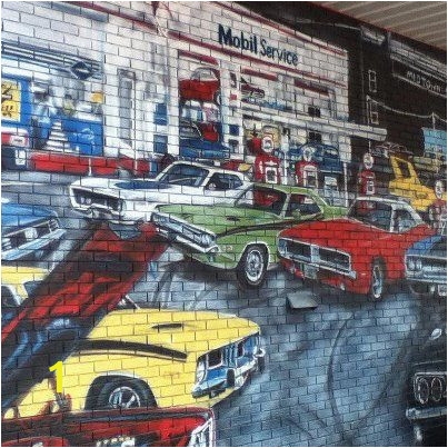 This wall mural is a tribute to the age of muscle cars and features a classic Challenger among some fast pany