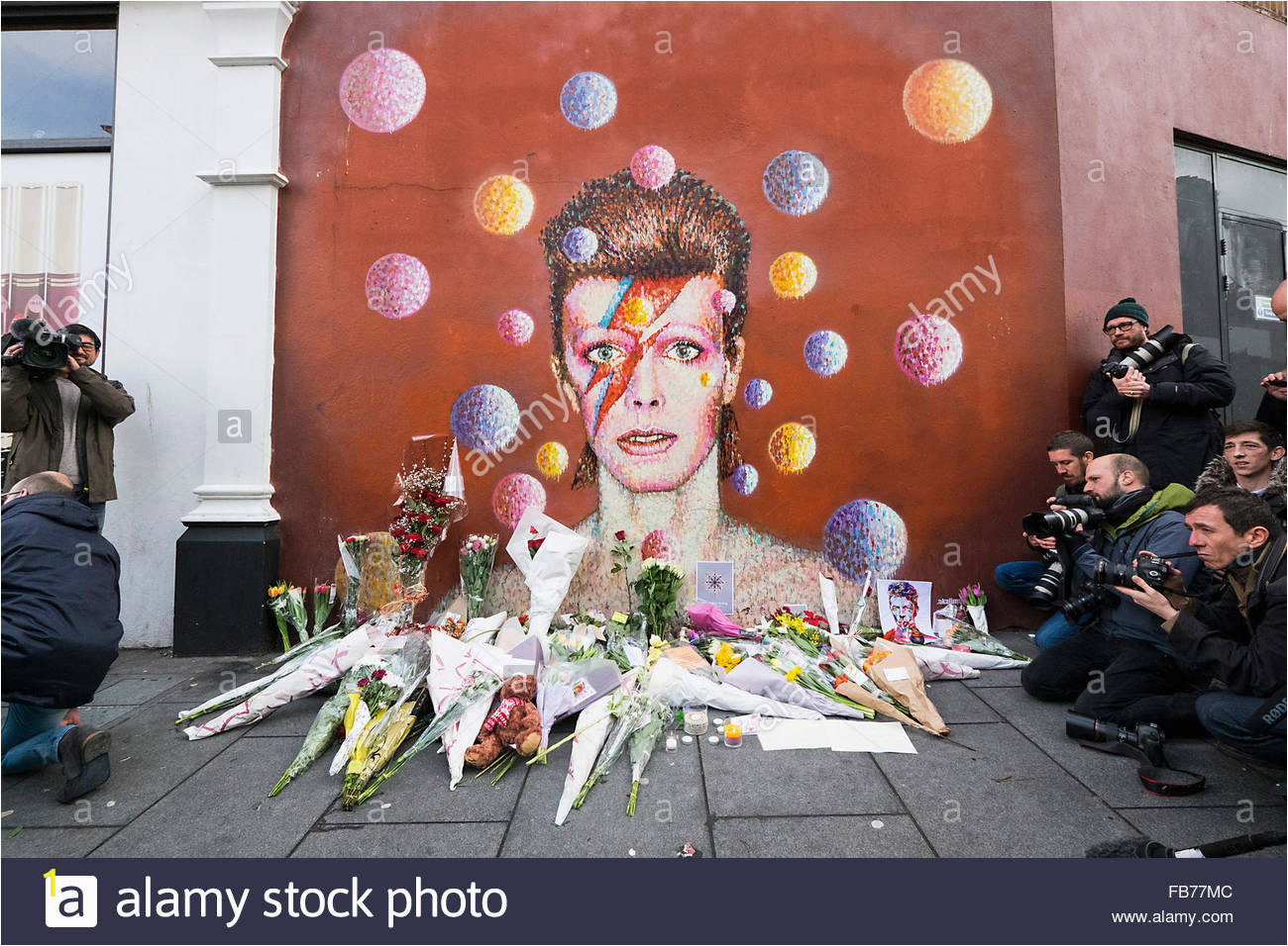 a mural of david bowie with tributes and flowers FB77MC