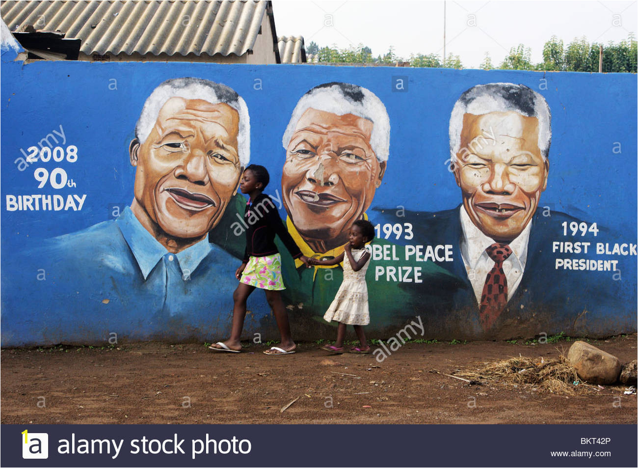 children passing a nelson mandela wall mural in the township soweto BKT42P