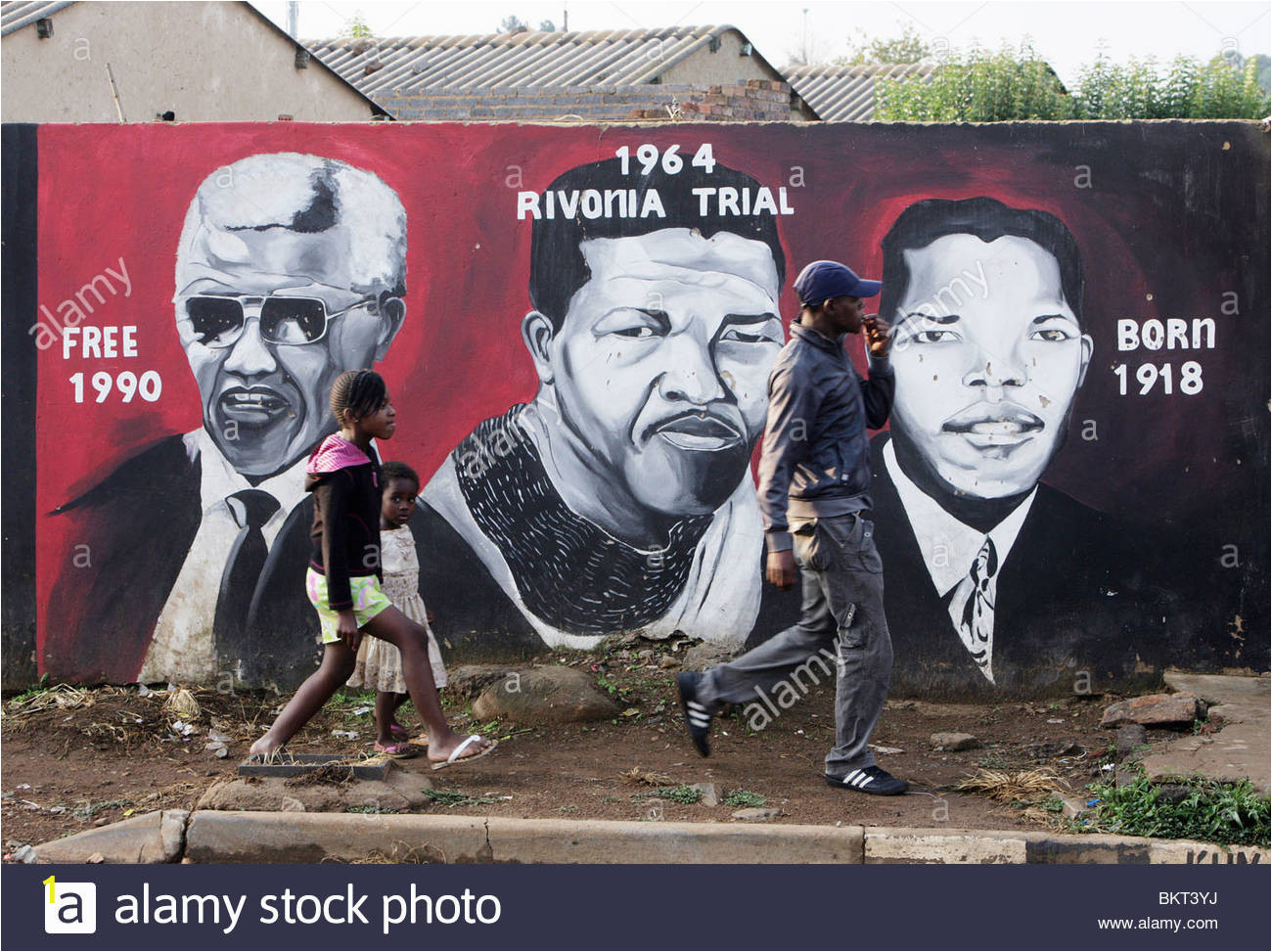 children passing a nelson mandela wall mural in the township soweto BKT3YJ